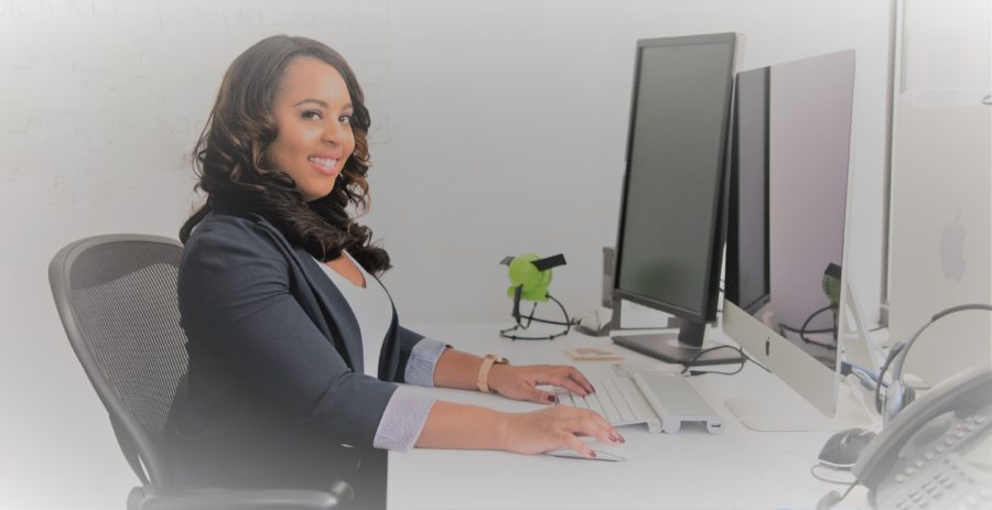 woman sitting upright at her desk workstation in front of a computer