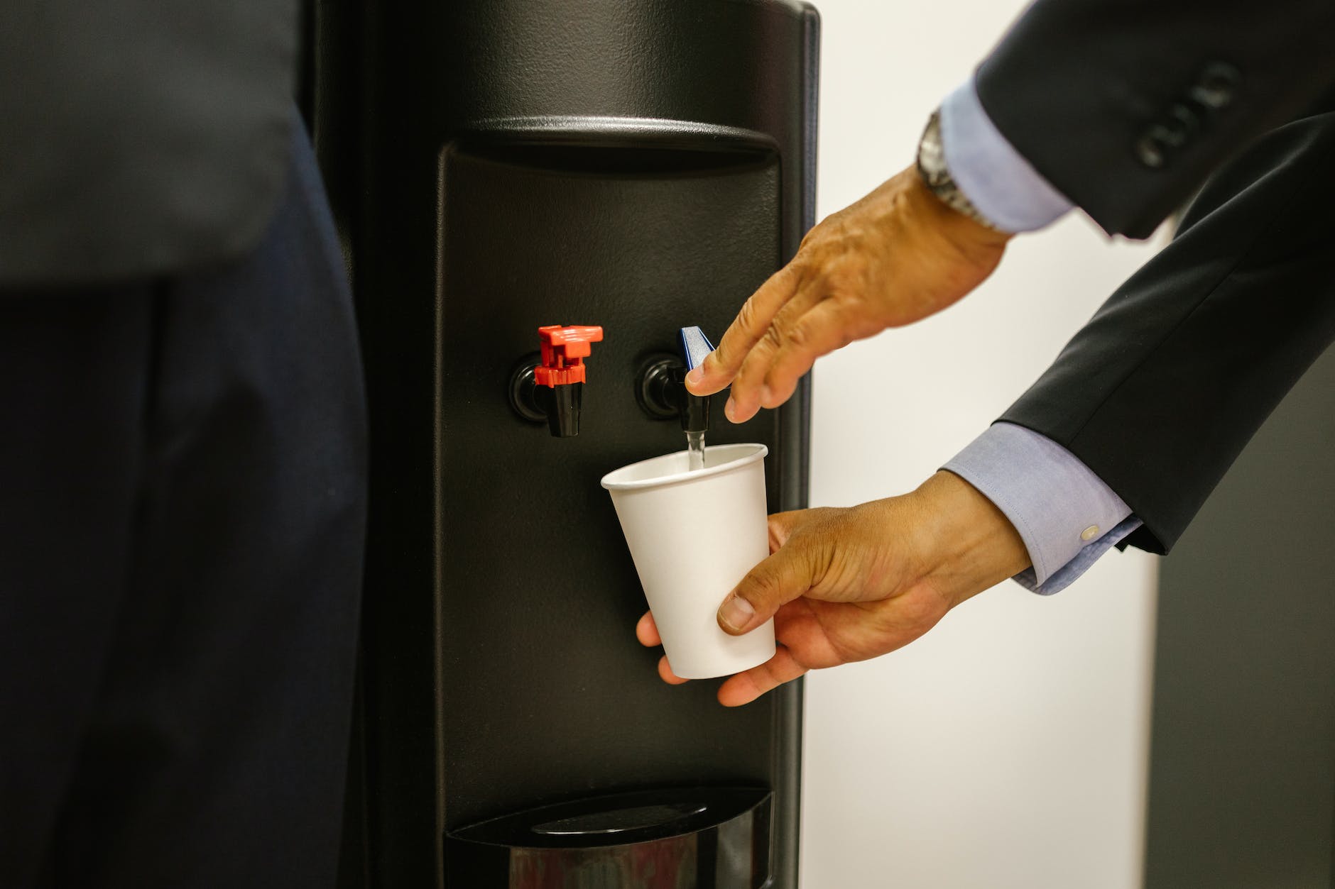 person pouring water on white cup